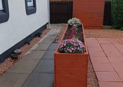 Timber planter built from decking boards beside a garden path