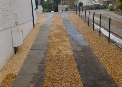 Finished slabbed path with gravel borders along the side of a house